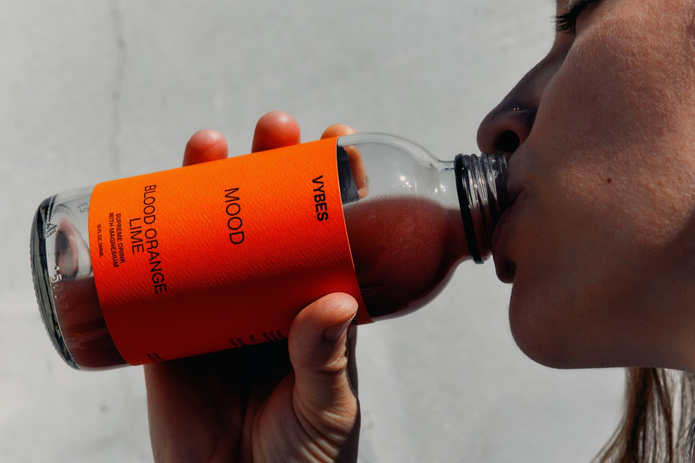 A woman drinking a VYBES Blood Orange Lime Mood drink